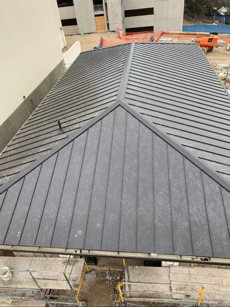 Commercial metal roof construction with crane equipment in Bridgton